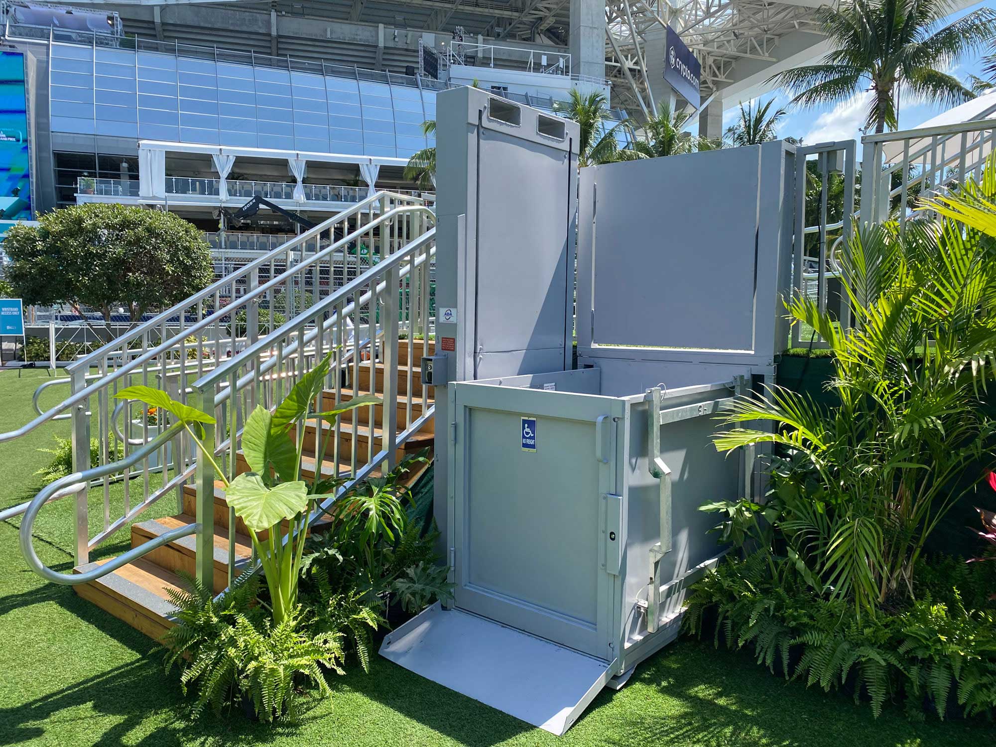 grey, 6' ADA wheelchair lift rental next to stairs to a hospitality center at the F1 Miami Grand Prix