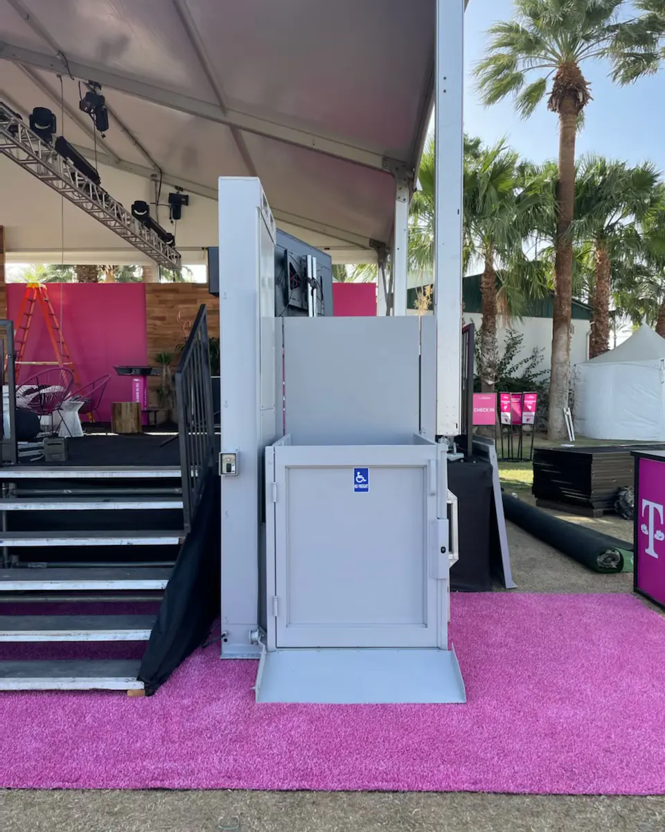 grey 6' ADA wheelchair lift rental at the stagecoach music festival shown next to stairs to a stage on a pink carpet