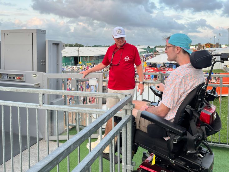 ADA Lift Rentals tech assisting a fan in a wheelchair at the New Orleans Jazz Festival.