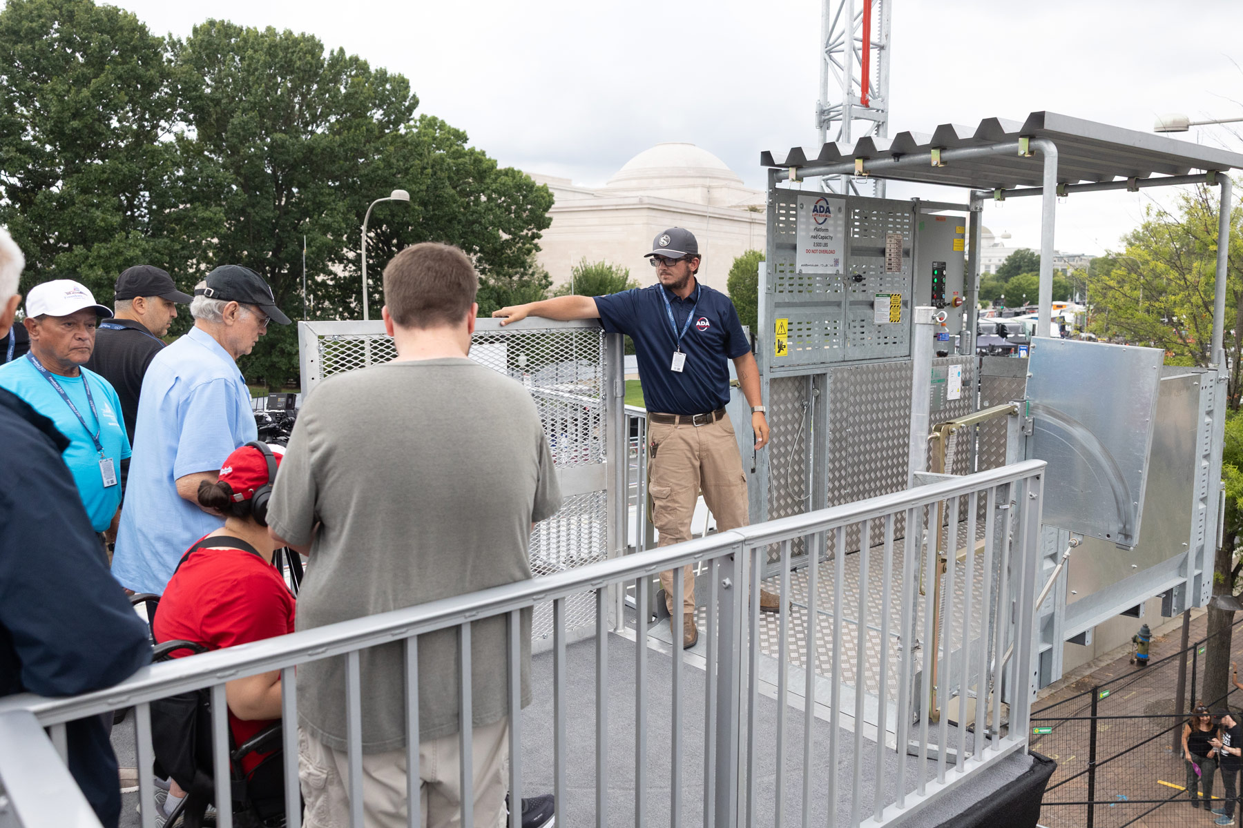 technician helping event attendees board ADA Lift Rentals' transport platform